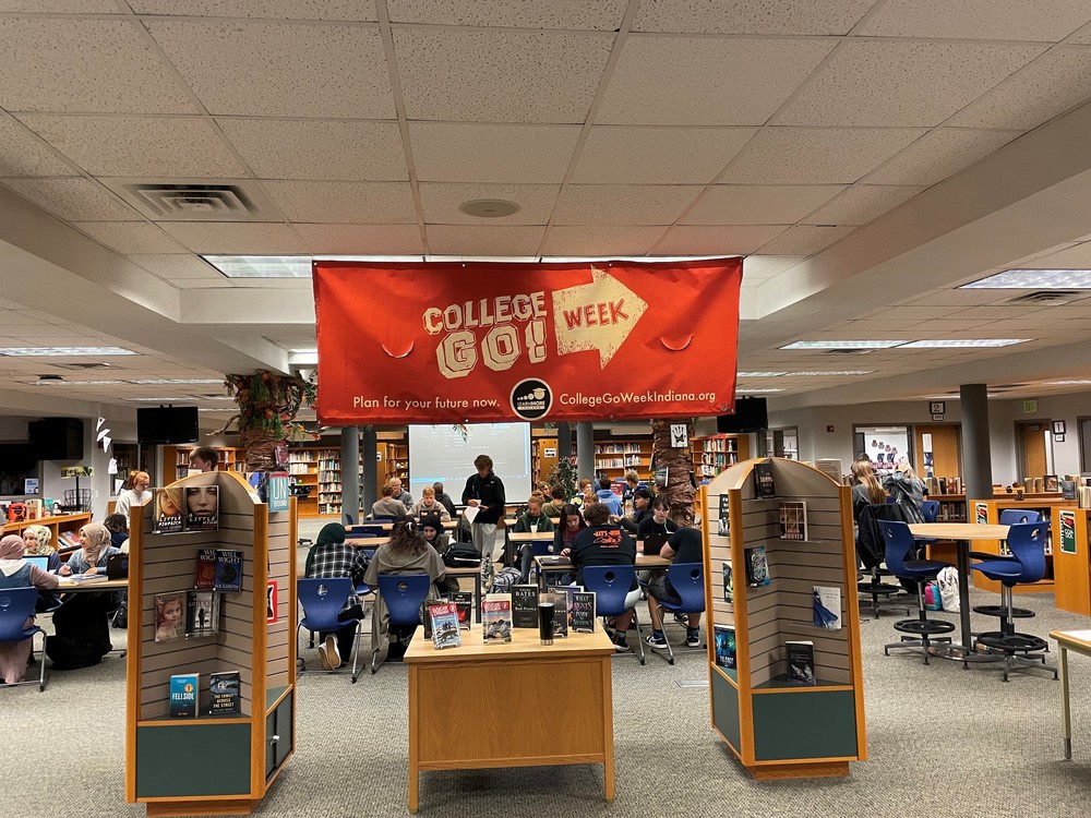 student in media center with college go week banner hanging from ceiling