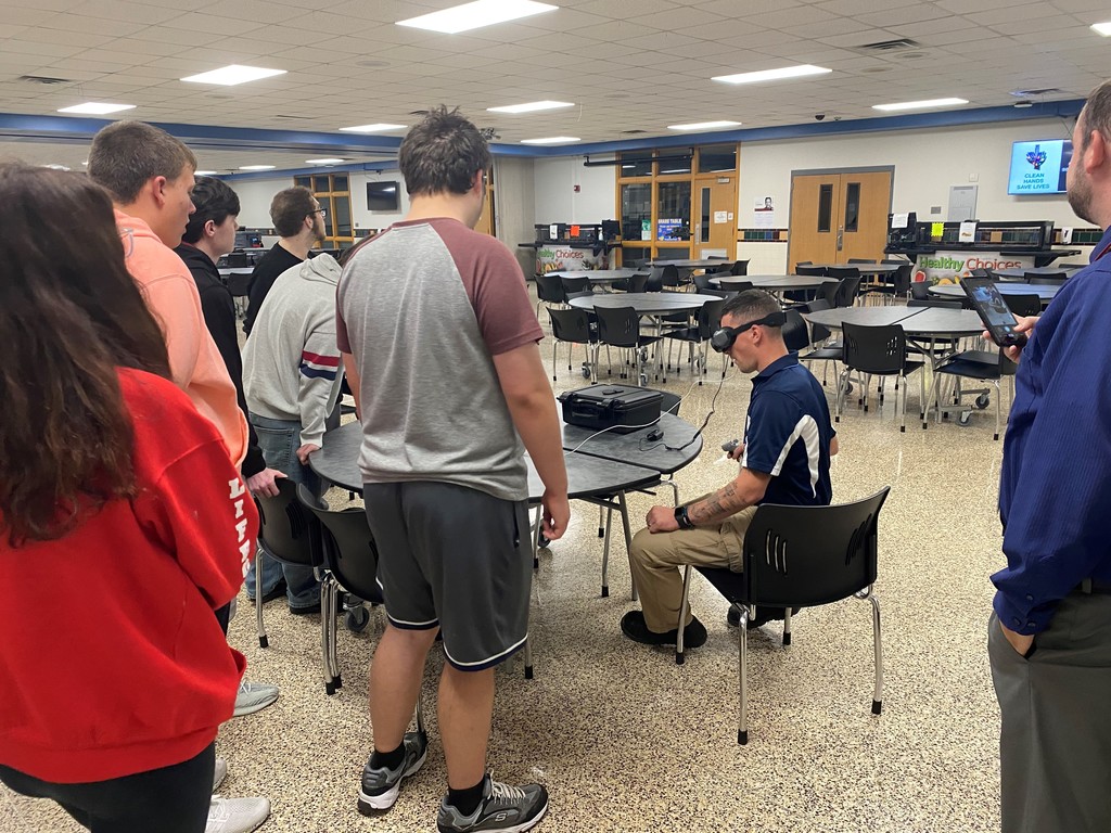 man using VR goggles in front of a group of students